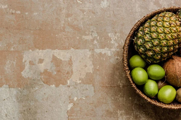 Vue de dessus des fruits exotiques mûrs dans le panier en osier sur la surface altérée — Photo de stock