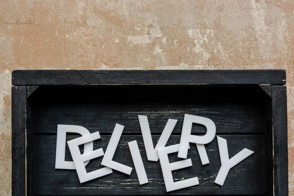 Верхний вид доставки слова в деревянном черном ящике на выветриваемую поверхность — стоковое фото