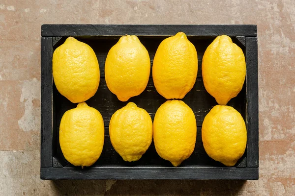 Vue de dessus des citrons dans la boîte noire en bois sur la surface altérée — Photo de stock