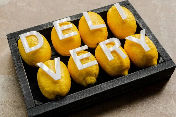 Word delivery on lemons in wooden black box on weathered surface — Stock Photo