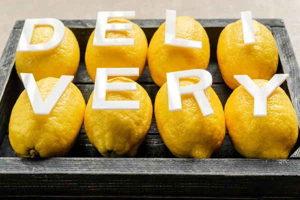 Word delivery on lemons in wooden black box on weathered surface — Stock Photo