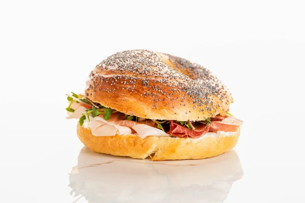 Bagel frais délicieux avec du prosciutto sur fond blanc — Photo de stock