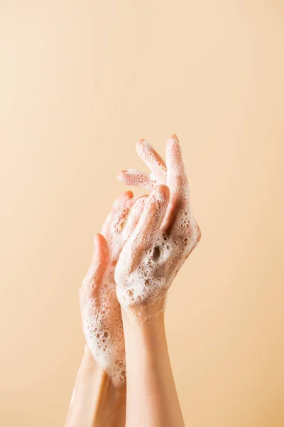 Vista cortada de mãos femininas em espuma de sabão isolado em bege — Fotografia de Stock