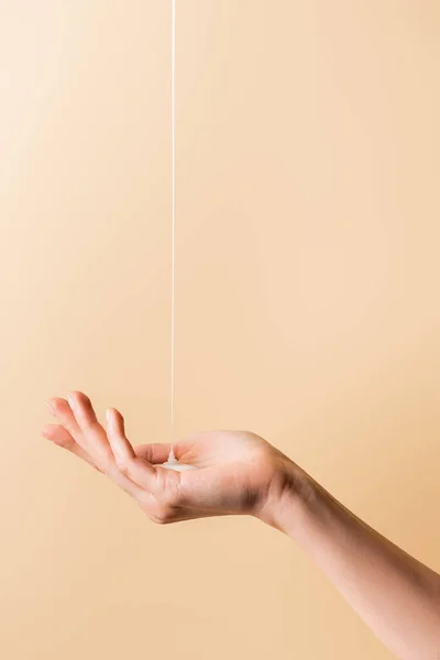 Cropped view of female hand under flowing liquid soap isolated on beige — Stock Photo