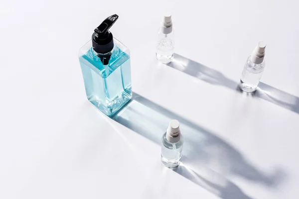 High angle view of transparent bottles with antiseptic liquid on white with shadows — Stock Photo