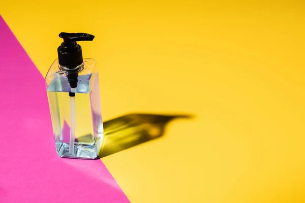 Disinfectant in transparent bottle on pink and yellow with shadow — Stock Photo