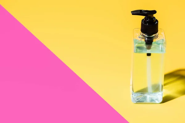 Antiseptic liquid in transparent bottle on pink and yellow with shadow — Stock Photo