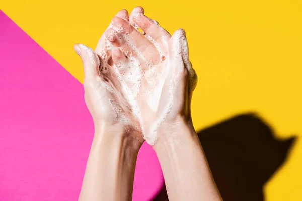 Vista ritagliata di mani femminili in schiuma di sapone su rosa e giallo — Foto stock