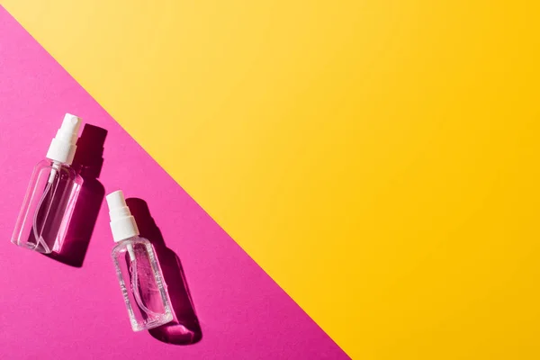 Top view of transparent spray bottles with disinfectant on pink and yellow — Stock Photo