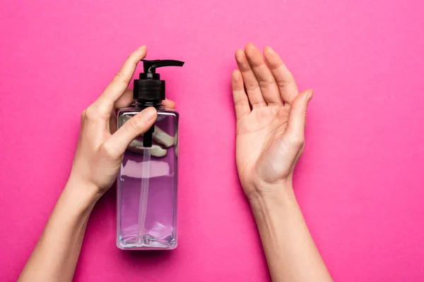 Cropped view of woman applying sanitizer on hand on pink — Stock Photo