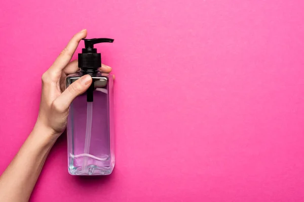 Частковий вид жінки, що тримає пляшку з антисептиком на рожевому — стокове фото