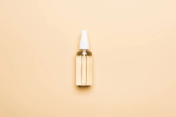 Vista superior de botella de spray transparente con desinfectante de manos en beige - foto de stock
