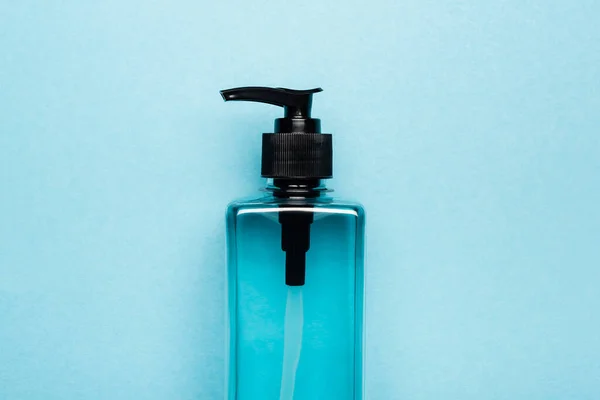 Ansicht von Hand antiseptisch in transparenter Flasche mit Spender auf blau — Stockfoto