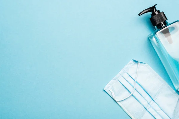 Vue du dessus du désinfectant pour les mains et du masque médical sur le concept bleu, covid-19 — Photo de stock