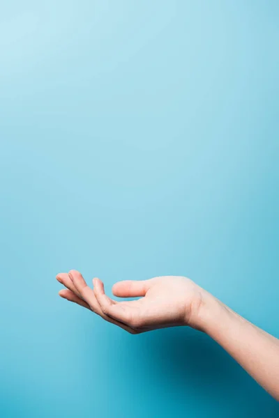 Vista recortada de la mano femenina con la palma abierta en azul - foto de stock