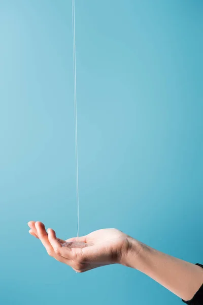 Vista recortada de la mano femenina bajo jabón líquido fluido en azul - foto de stock