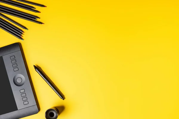 Вид зверху на планшет, барвисті олівці та стилус на жовтому — стокове фото