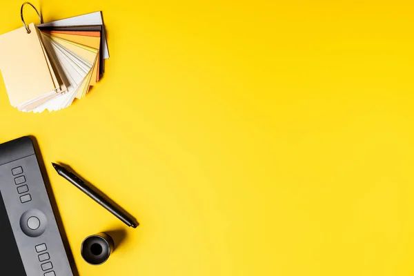 Top view of drawing tablet, palette and color pencils near stylus on yellow — Stock Photo