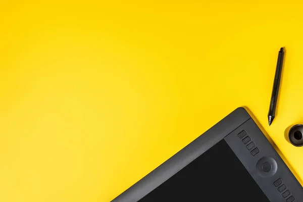 Vista superior de la tableta de dibujo cerca del soporte de lápiz y lápiz en amarillo - foto de stock
