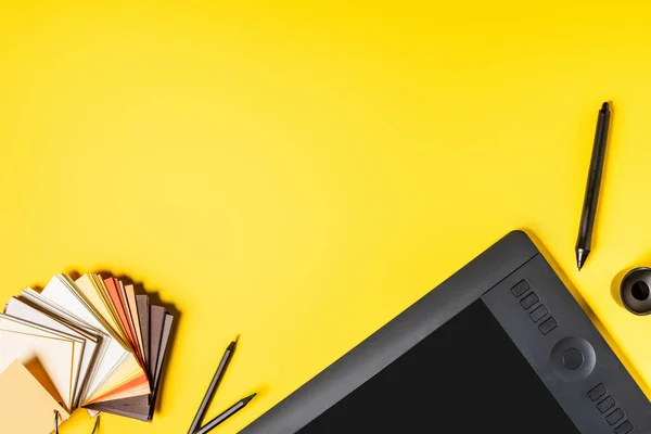 Top view of drawing tablet with blank screen, catalog with palette and color pencils near stylus on yellow — Stock Photo