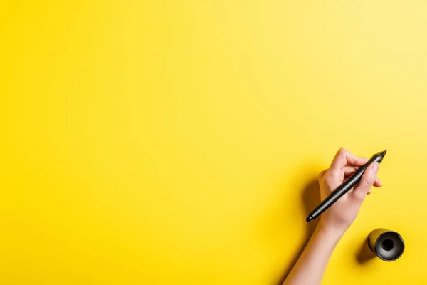 Vista recortada del diseñador sosteniendo lápiz cerca del soporte de lápiz en amarillo - foto de stock