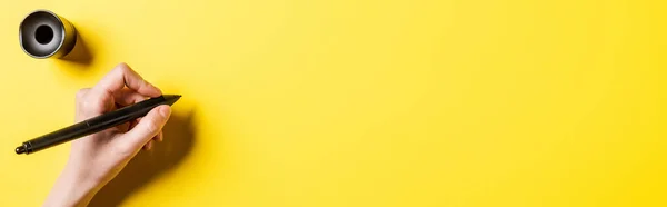 Horizontal image of designer holding stylus near stylus holder on yellow — Stock Photo