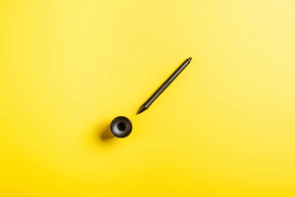 Top view of black stylus near holder on yellow — Stock Photo