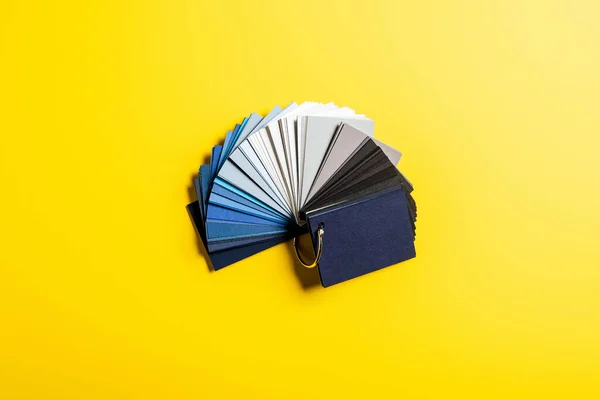 Top view of palette with blue, grey and black colors on yellow — Stock Photo