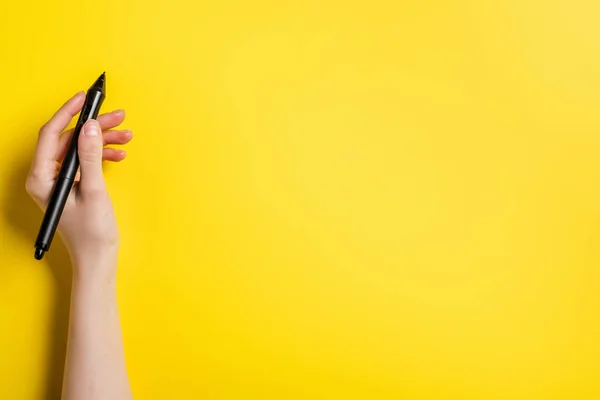 Cropped view of designer holding black stylus on yellow — Stock Photo