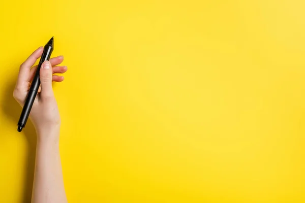 Vista ritagliata del progettista che tiene lo stilo nero sul giallo — Foto stock