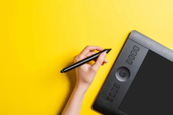 Cropped view of designer holding stylus near drawing tablet with blank screen on yellow — Stock Photo