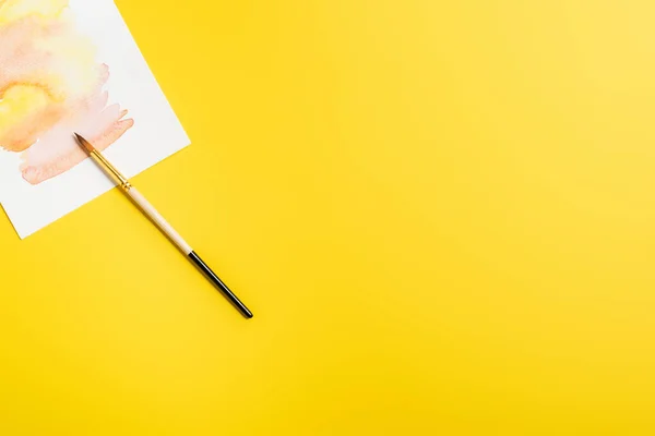 Vue de dessus du pinceau près de la peinture créative isolée sur jaune — Photo de stock