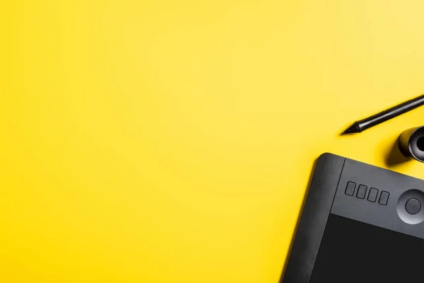 Top view of stylus near drawing tablet on yellow — Stock Photo