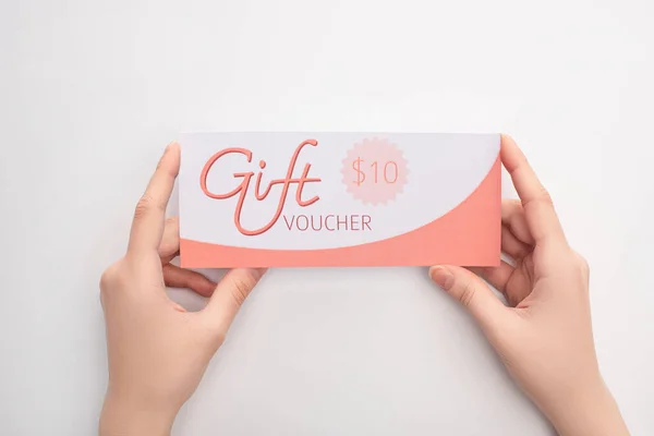 Top view of woman holding gift voucher with 10 dollars sign on white background — Stock Photo