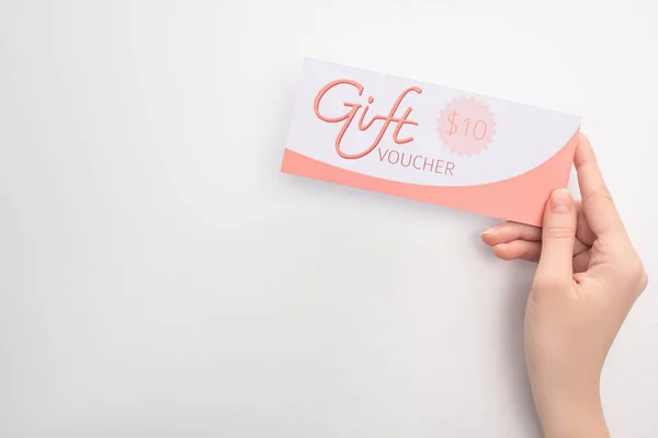 Top view of woman holding gift voucher with 10 dollars sign on white surface — Stock Photo