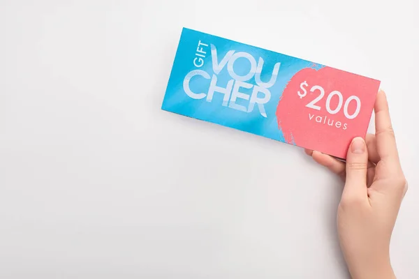 Vue du dessus de la femme tenant un chèque-cadeau avec 200 valeurs lettrage sur fond blanc — Photo de stock
