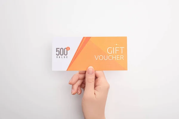 Top view of woman holding gift voucher with 500 value lettering on white background — Stock Photo