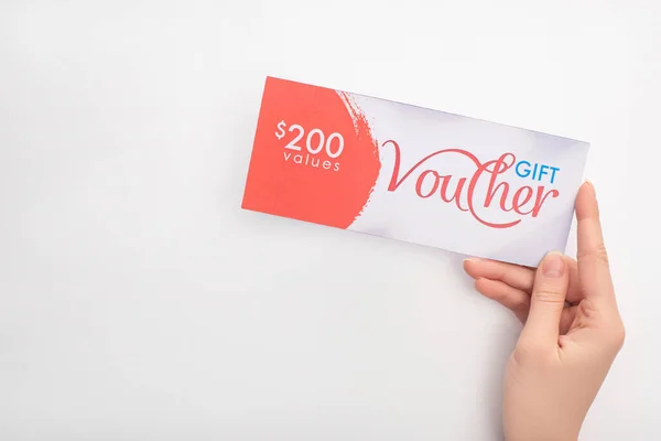 Top view of woman holding gift voucher with dollar sign and values lettering on white background — Stock Photo