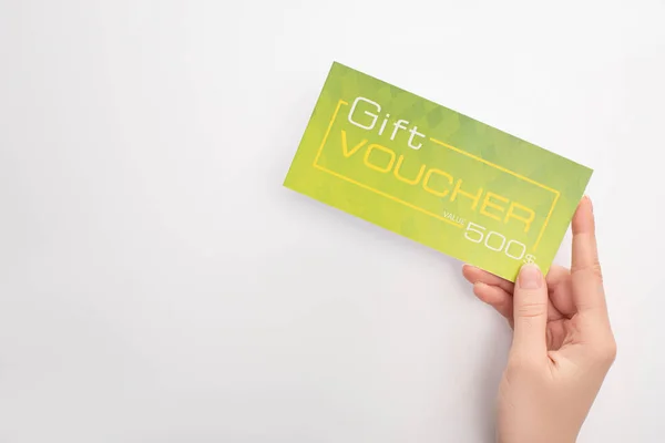 Visão superior da mulher segurando voucher presente verde no fundo branco — Fotografia de Stock