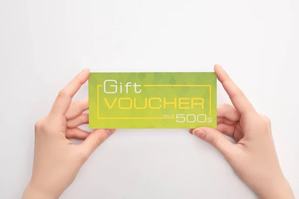 Vue recadrée de la femme tenant un chèque-cadeau vert avec lettrage de valeur sur fond blanc — Photo de stock
