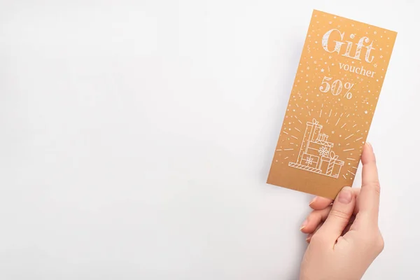 Vista superior de la mujer que sostiene el cupón de regalo de oro con 50 por ciento signo sobre fondo blanco - foto de stock