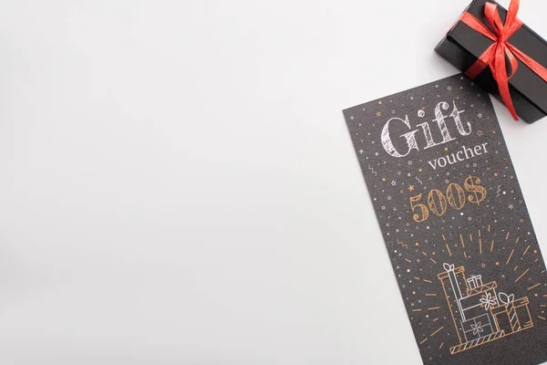 Top view of gift voucher near black present on white background — Stock Photo