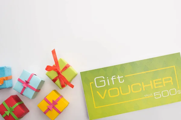 Top view of gift boxes near green gift voucher on white background — Stock Photo