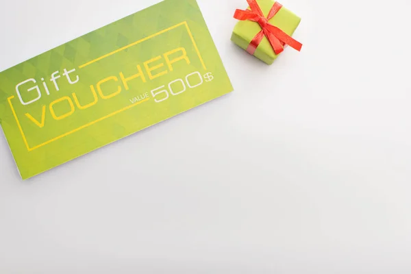 Top view of gift voucher and present on white background with copy space — Stock Photo