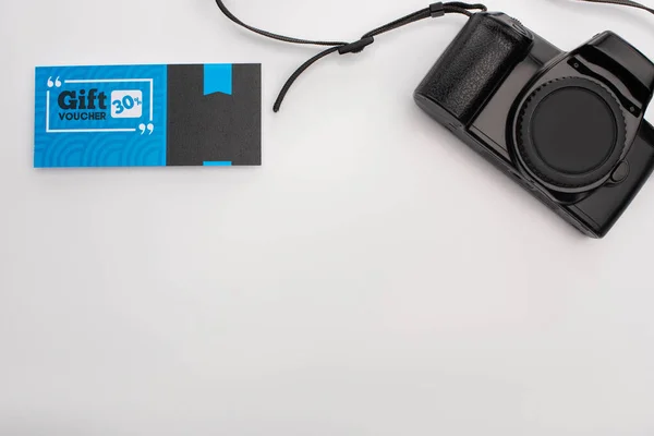 Вид зверху подарункового ваучера біля цифрової камери на білій поверхні з копіювальним простором — стокове фото
