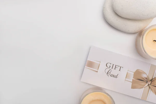 Top view of gift card, zen stones and candles on white background — Stock Photo