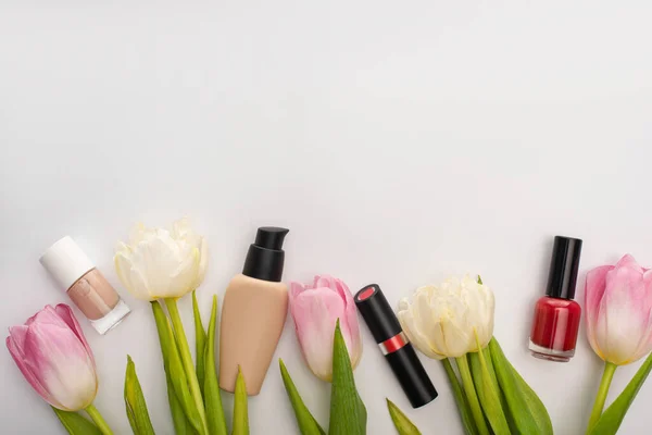 Vista superior de tulipas com folhas e cosméticos decorativos no fundo branco — Fotografia de Stock