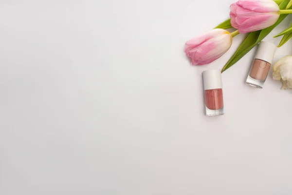 Top view of nail polishes and tulips on white background — Stock Photo