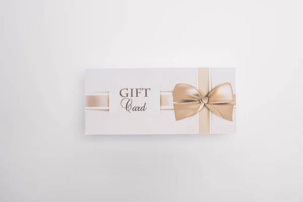 Vue du dessus de la carte cadeau avec arc sur fond blanc — Photo de stock