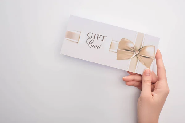 Cropped view of woman holding gift card with bow on white background — Stock Photo